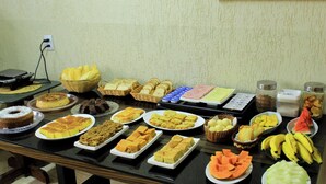 A buffet table with various food items including cakes, pastries, and fruits. - Pousada Dos Atobás (Arraial do Cabo)