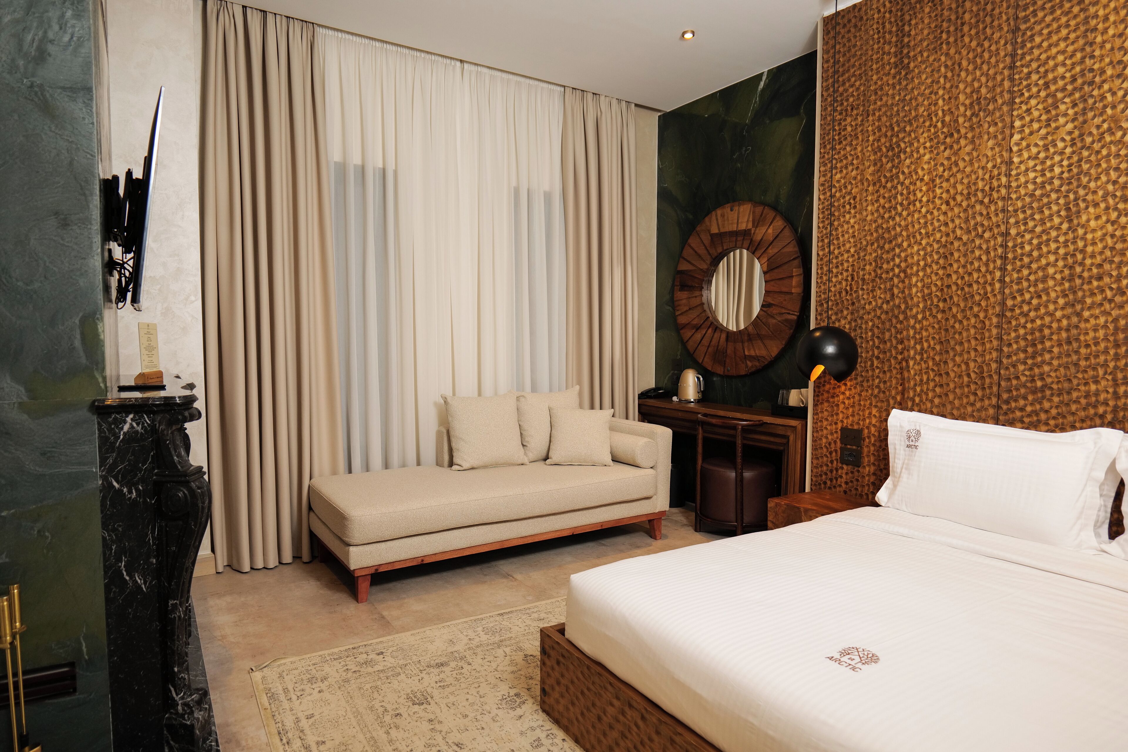Habitación de hotel con cama, sofá, escritorio y un espejo grande.