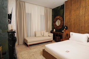 Habitación de hotel con cama, sofá, escritorio y un espejo grande.
