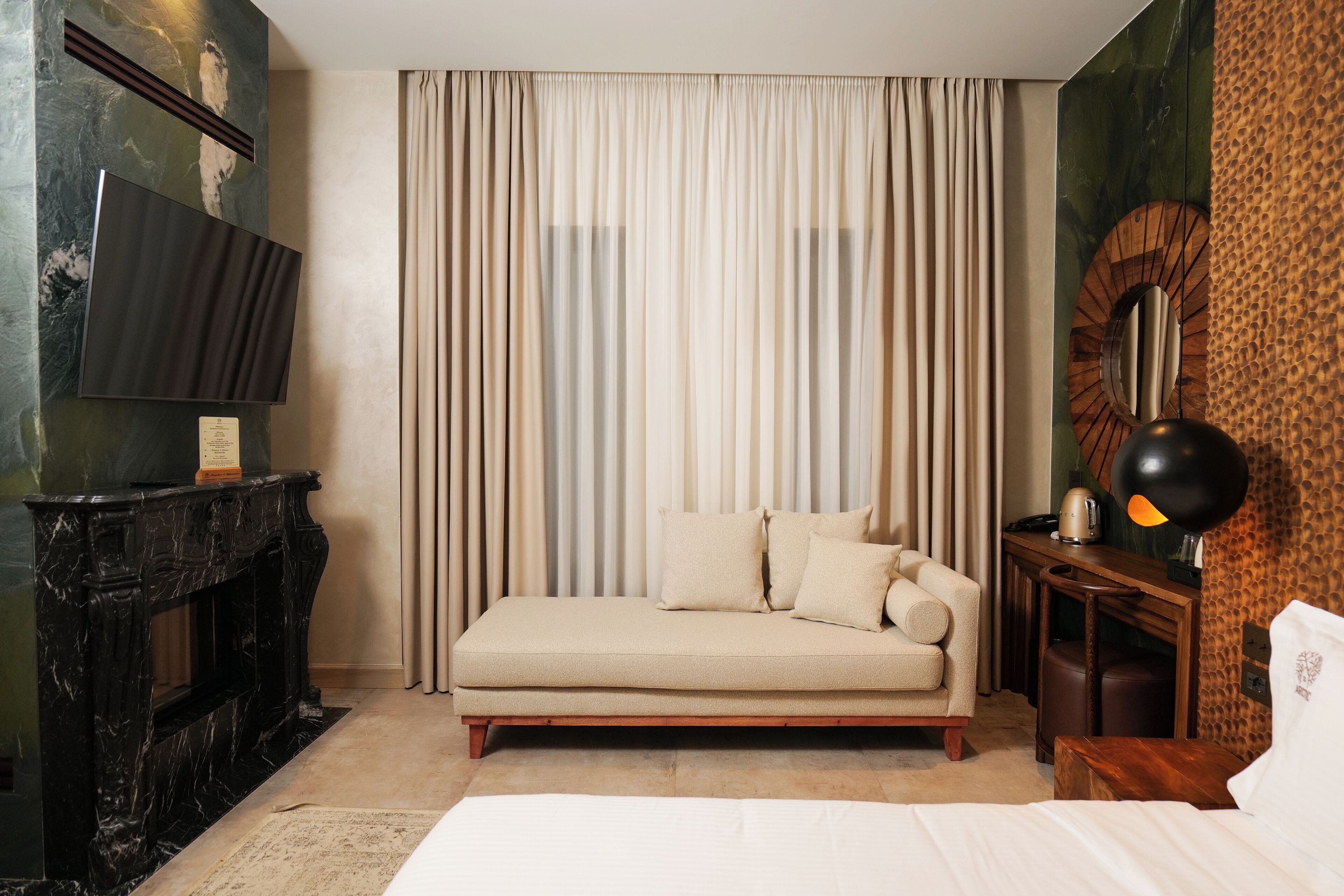 A hotel room with a sofa, a television, a fireplace, and a lamp.