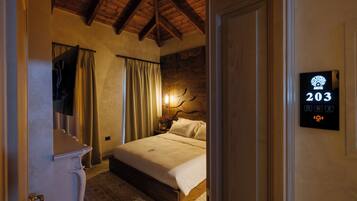 Habitación de hotel con cama, cortinas, una lámpara fijada a la pared y un cartel con el número de la habitación.