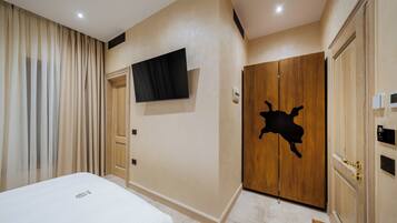Habitación de hotel con cama, televisor montado en la pared, armario de madera de diseño único y una puerta con interruptor de luz.