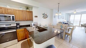 A modern kitchen with wooden cabinets, a built-in oven, and a granite countertop. - Master on Gulf & close to Everything & Free round of Golf & Activities Daily! (Panama City Beach)