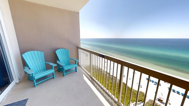 A balcony with two turquoise Adirondack chairs, a view of the ocean, and a sandy beach with umbrellas. - Master on Gulf & close to Everything & Free round of Golf & Activities Daily! (Panama City Beach)