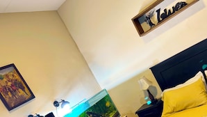 A bedroom with a bed, a nightstand, a lamp, a framed picture, and a fish tank. - Relax room: beautiful fish and plants (Cochabamba)