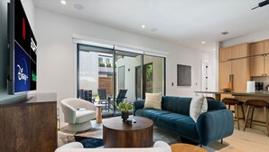 A modern living room with a sofa, chairs, a coffee table, and a TV displaying Disney+ and Hulu logos.