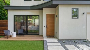 A modern house with a covered patio, a sliding glass door, and a wooden door.