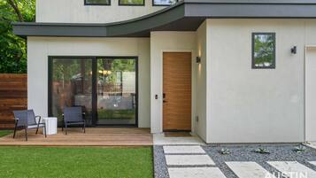 Une maison moderne dotée d’un patio couvert, d’une porte-fenêtre coulissante et d’une porte en bois.