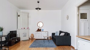 A modern living room with a wooden floor, a black office chair, a grey sofa, a white dresser, and a ceiling fan. - Vintage 1BR Apt in Kamppi  (Helsinki)