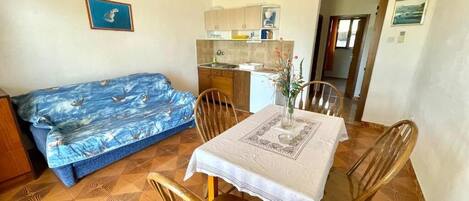 A compact living space with a kitchenette, a dining table with chairs, a sofa, and a small kitchen area.
