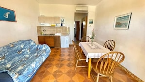 Een compacte woonruimte met een kitchenette, een zithoek met een tafel en stoelen, en een bank.