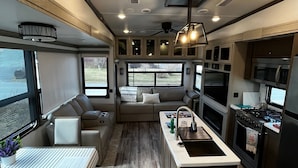 A compact kitchen with a central island, built-in appliances, and a seating area with a view. - Luxury 1-bedroom RV with AC, WiFi in charming Bonavista (Bonavista)