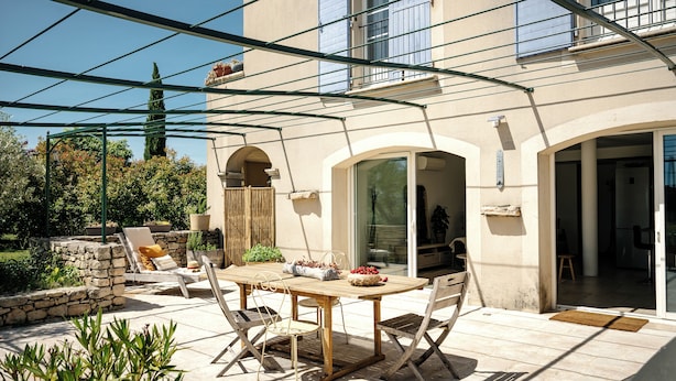 Eine Terrasse im Freien mit Tisch und Stühlen, einer Pergola und einer Steinmauer.