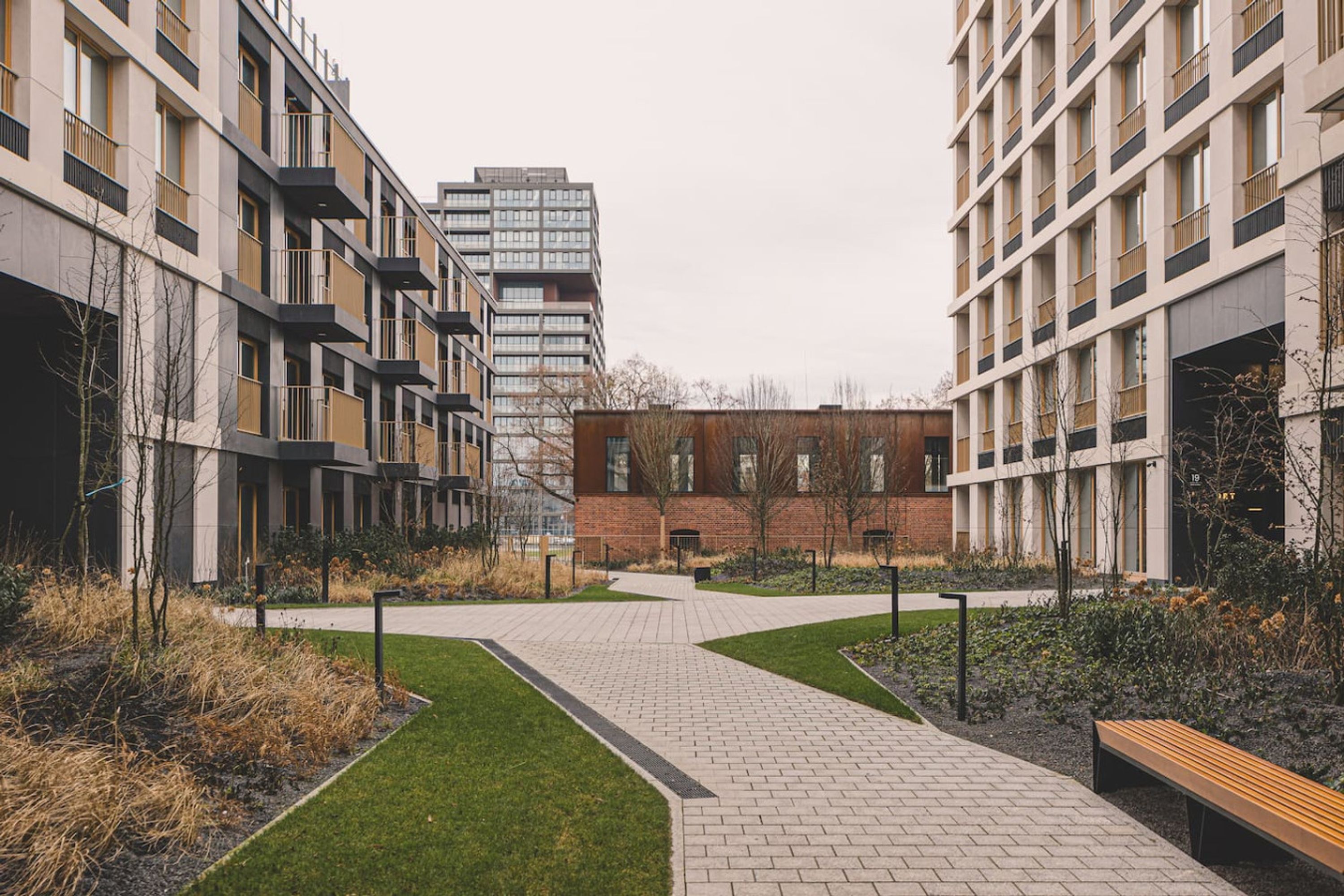 A modern building complex with a central courtyard, featuring a paved walkway and benches.
