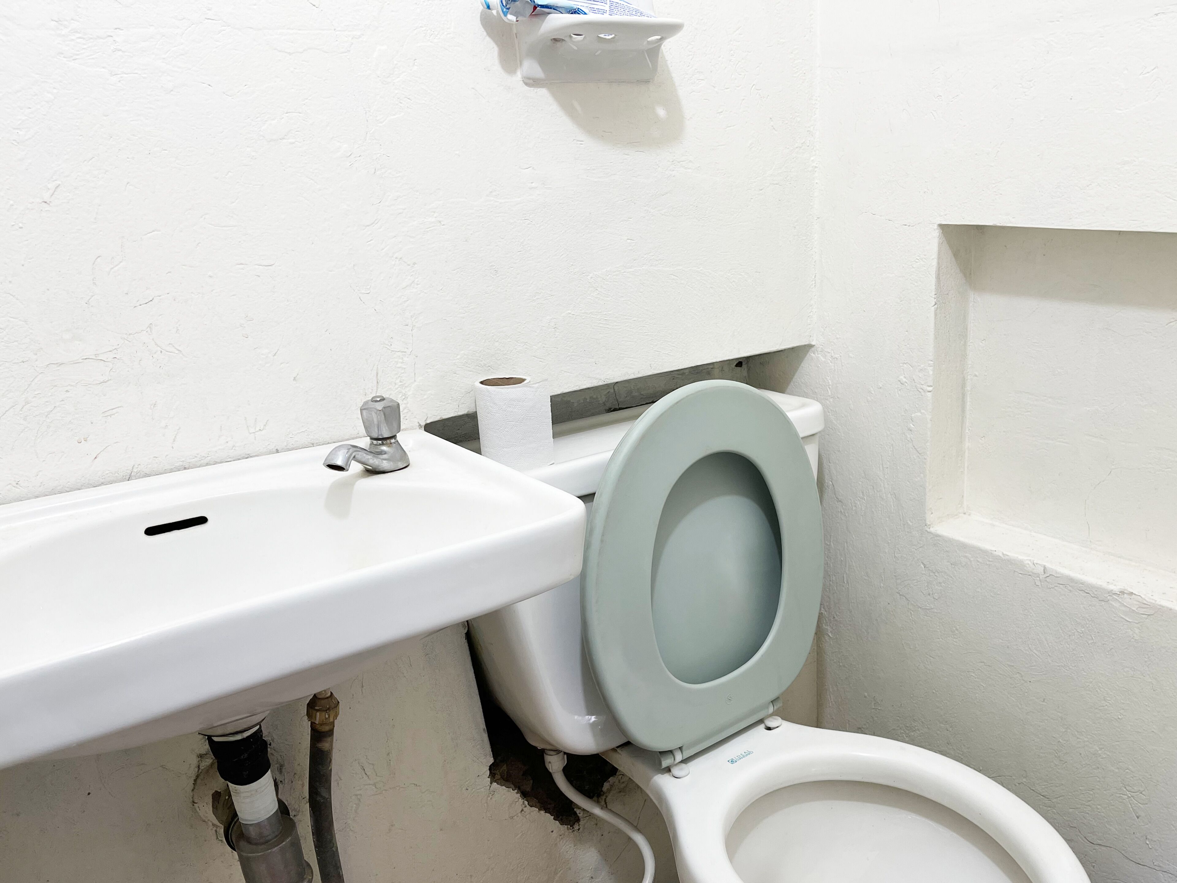 Un baño con un lavabo blanco, un inodoro y un dispensador de toallas de papel en la pared.