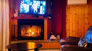 A cozy living room with a fireplace, a television mounted above it, and a leather couch.