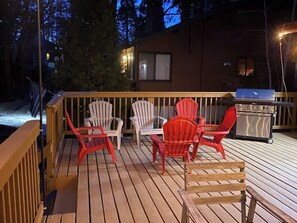 Eine Holzterrasse mit Sitzgelegenheit und Grill.