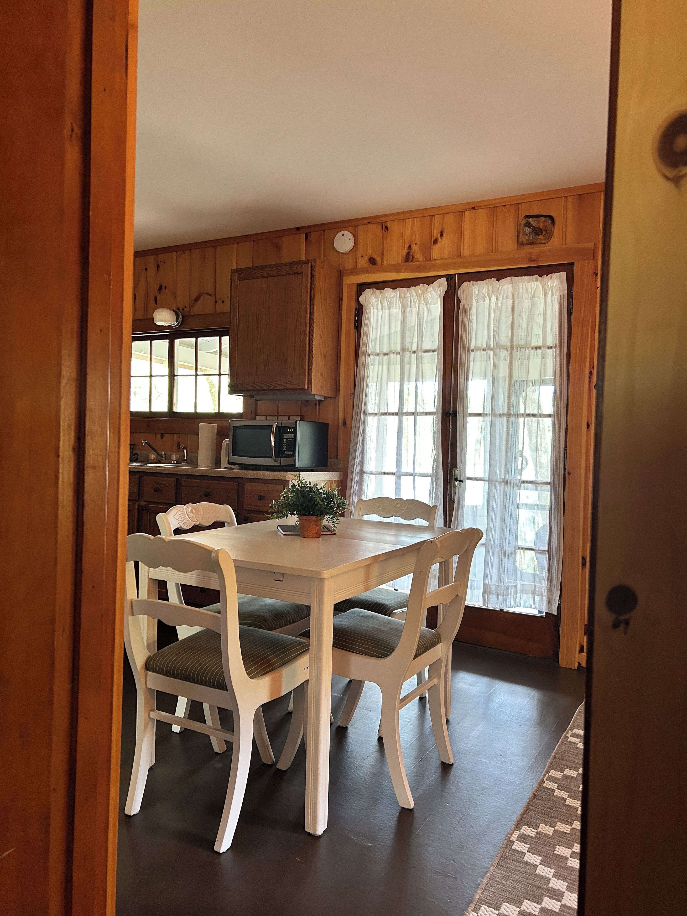 Un interior de madera con una mesa de comedor y sillas, un microondas y una planta en maceta.