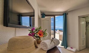 A room with a large mirror, a hat, a rolled towel, and a vase of flowers.
