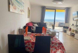 A dining area with a table set for four, a sofa, and a balcony with a view.