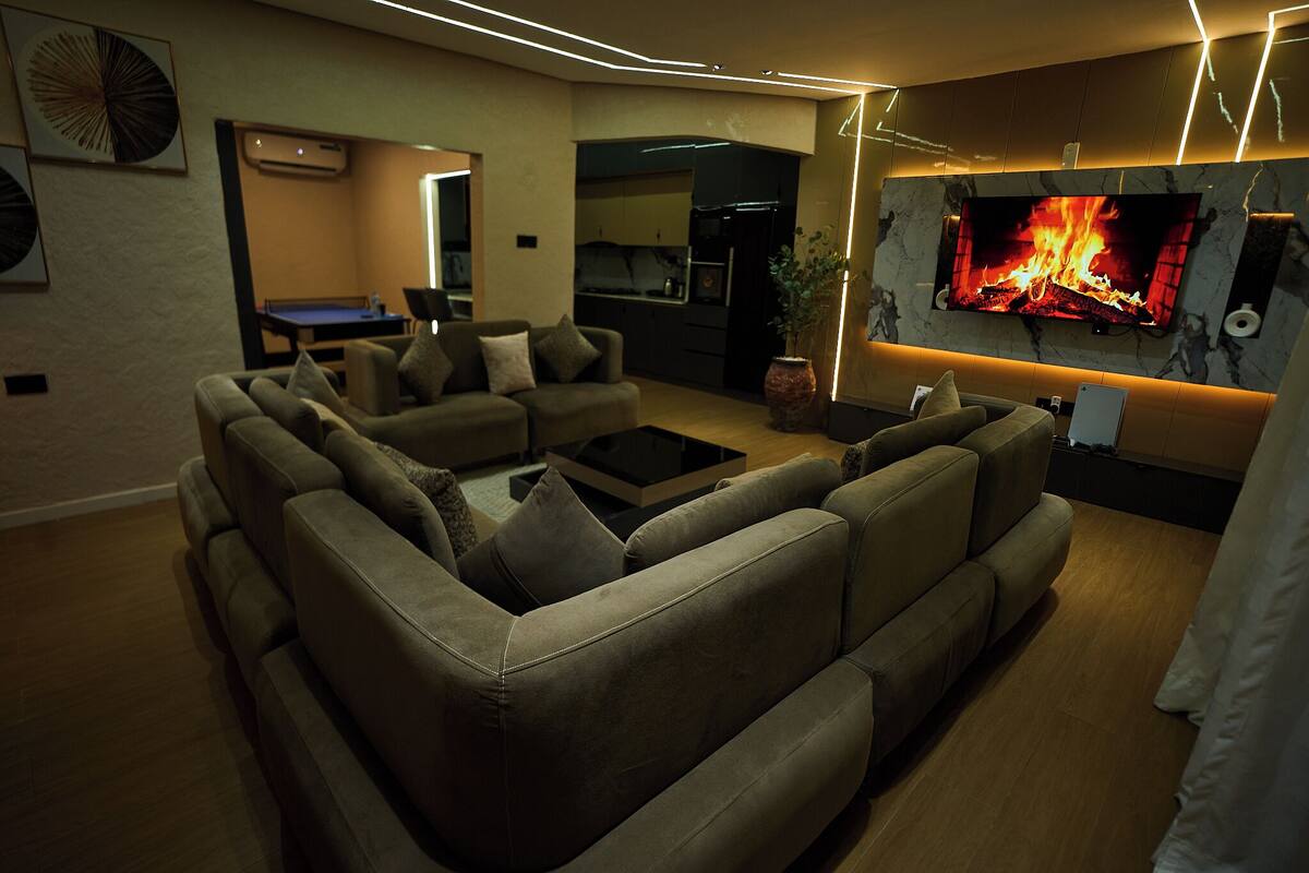 A modern living room with a sectional sofa, a flat-screen TV, and a fireplace.