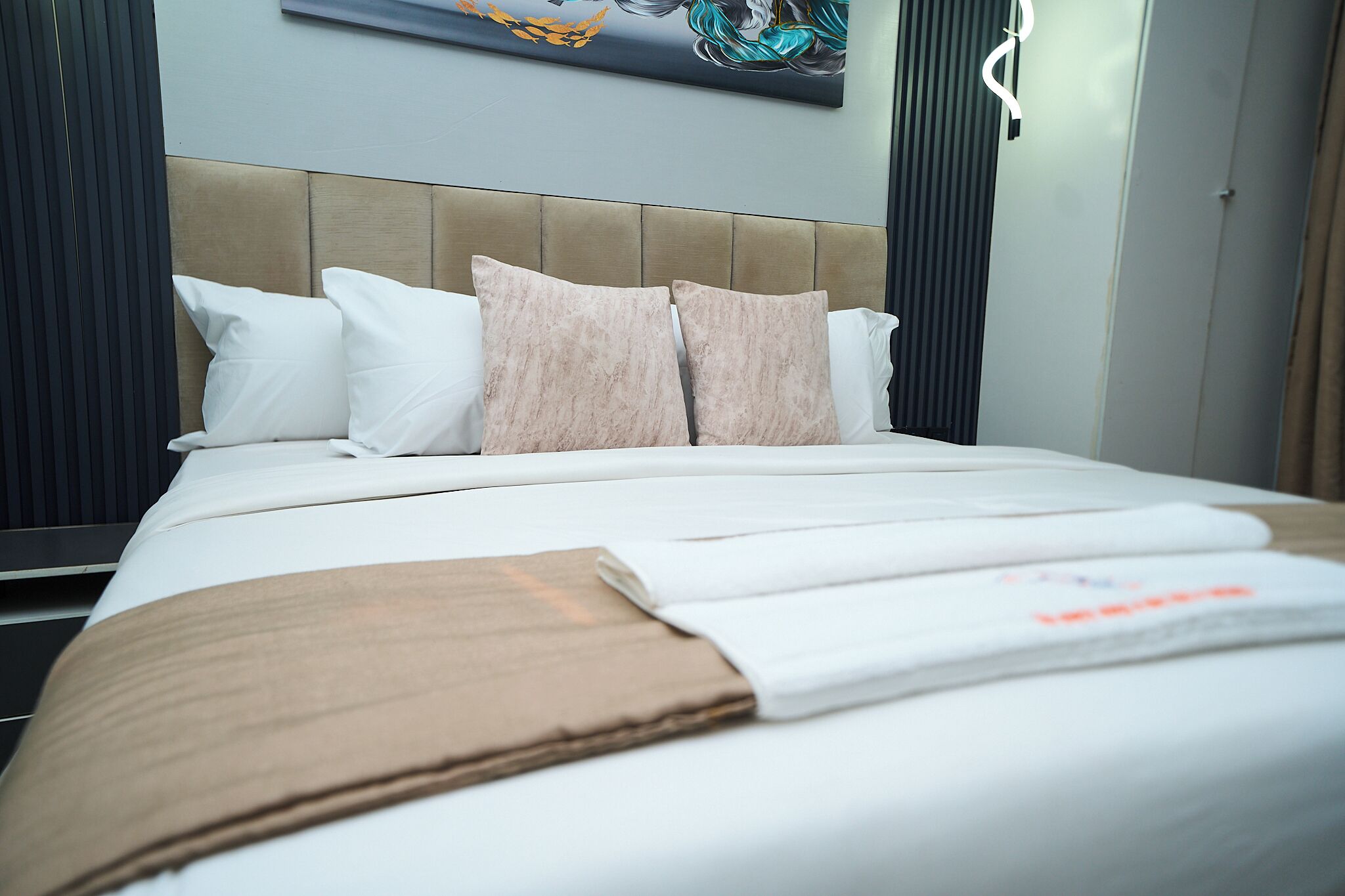 A neatly made bed with a headboard, pillows, and a blanket.