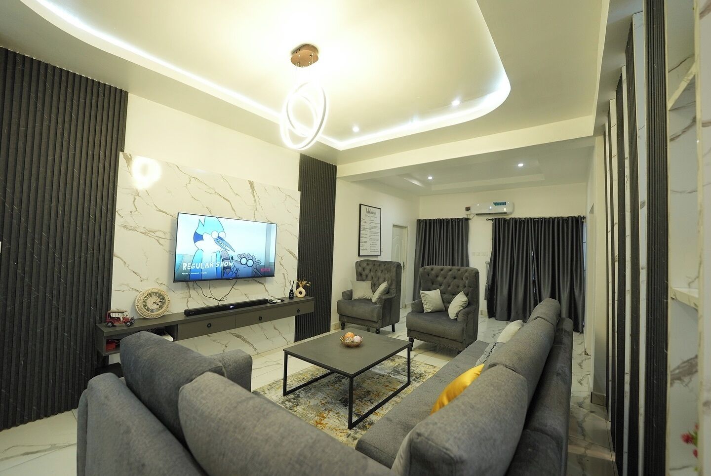 A modern living room with a TV, sofas, a coffee table, and a fireplace.