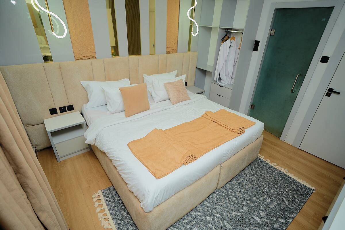 A neatly arranged bedroom with a bed, bedside tables, a wardrobe, and a mirror.
