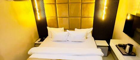 Una habitación de hotel con una cama grande, mesitas de noche, una lámpara de noche y un aire acondicionado instalado en la pared.