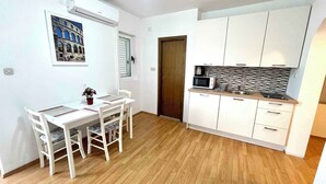 A compact kitchen with white cabinets, a microwave, and a tiled backsplash. - Villa Julie (Jadranovo)