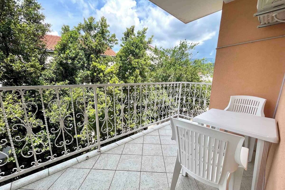 A balcony with a white metal railing, a white table, and a white chair.