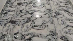 Un largo pasillo estrecho con piso de mármol y paredes blancas.