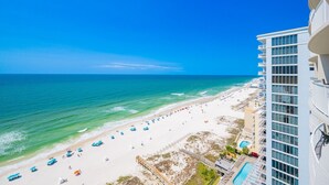 A beach view from a high-rise building with a pool and a beach with umbrellas. - Phoenix Gulf Shores Ii 1604 3 Bedroom Condo (Gulf Shores)