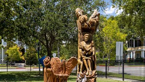 Una escultura de madera que muestra a una familia en un parque.