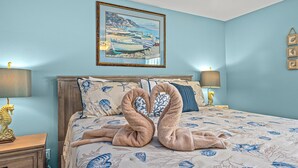 Un dormitorio con una cama, dos lámparas de noche, un cuadro enmarcado y una mesita de noche de madera.