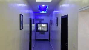 Un couloir doté d’un plafond au design moderne, comprenant des luminaires encastrés et un luminaire central.