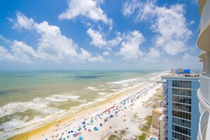 A beach with a view of the ocean and a building with balconies.