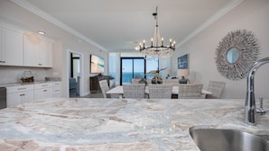 A spacious kitchen with a large marble island, modern appliances, and a view to the outside. - Phoenix Gulf Shores Ii 2003 3 Bedroom Condo (Gulf Shores)