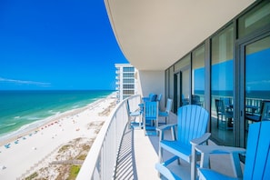 A balcony with blue chairs overlooking a beach. - Phoenix Gulf Shores Ii 1604 3 Bedroom Condo (Gulf Shores)
