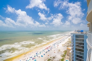 A beach with a view of the ocean and a building with balconies.