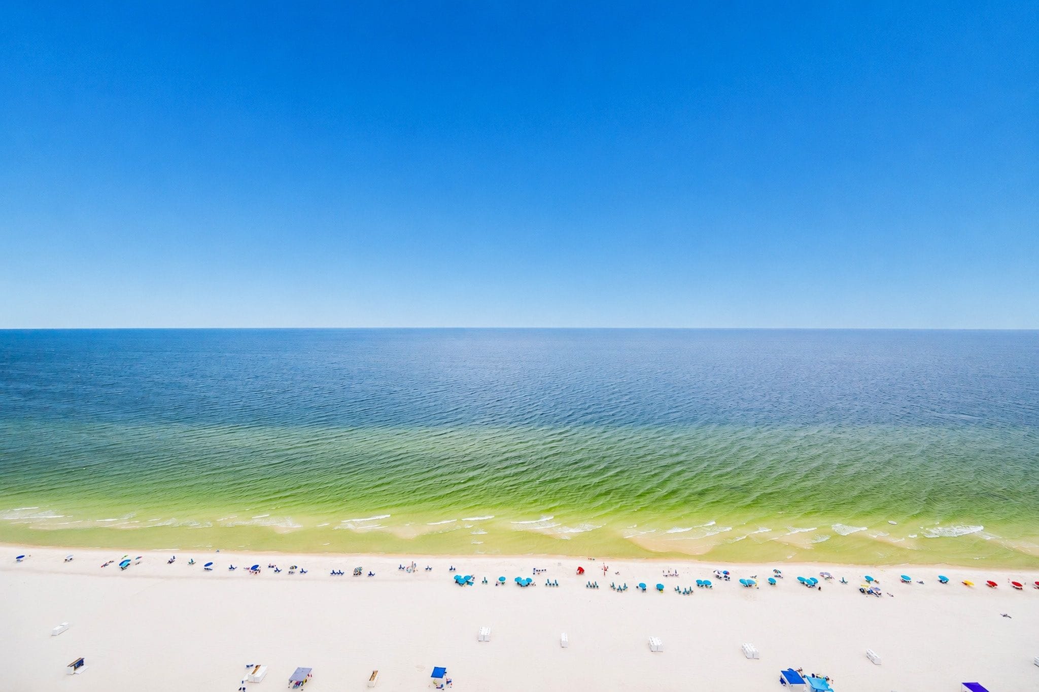 Une plage avec une eau d’un bleu limpide et un rivage sablonneux.