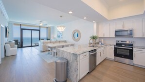 A modern kitchen with white cabinetry, a built-in oven, and a large island with a sink. - Phoenix Gulf Shores Ii 2504 3 Bedroom Condo (Gulf Shores)