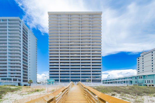 A modern hotel with a central tower and two side wings, connected by a wooden walkway. - Phoenix Gulf Shores Ii 2303 3 Bedroom Condo (Gulf Shores)