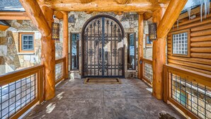 A log cabin entrance with a large wooden door, stone walls, and a stone staircase leading to the upper floor. - Bridge To Solitude 6 Bedroom Home (Breckenridge)