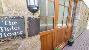 A stone building with a wooden door and a sign reading "The Baler House". - The Baler House (Hayle)