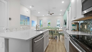 A modern kitchen with a central island, stainless steel appliances, and a dining area with a table and chairs.