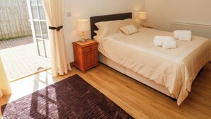 Un dormitorio con una cama, dos lámparas de noche, una mesita de noche de madera, una alfombra marrón oscuro y vistas a un patio a través de una puerta de cristal.