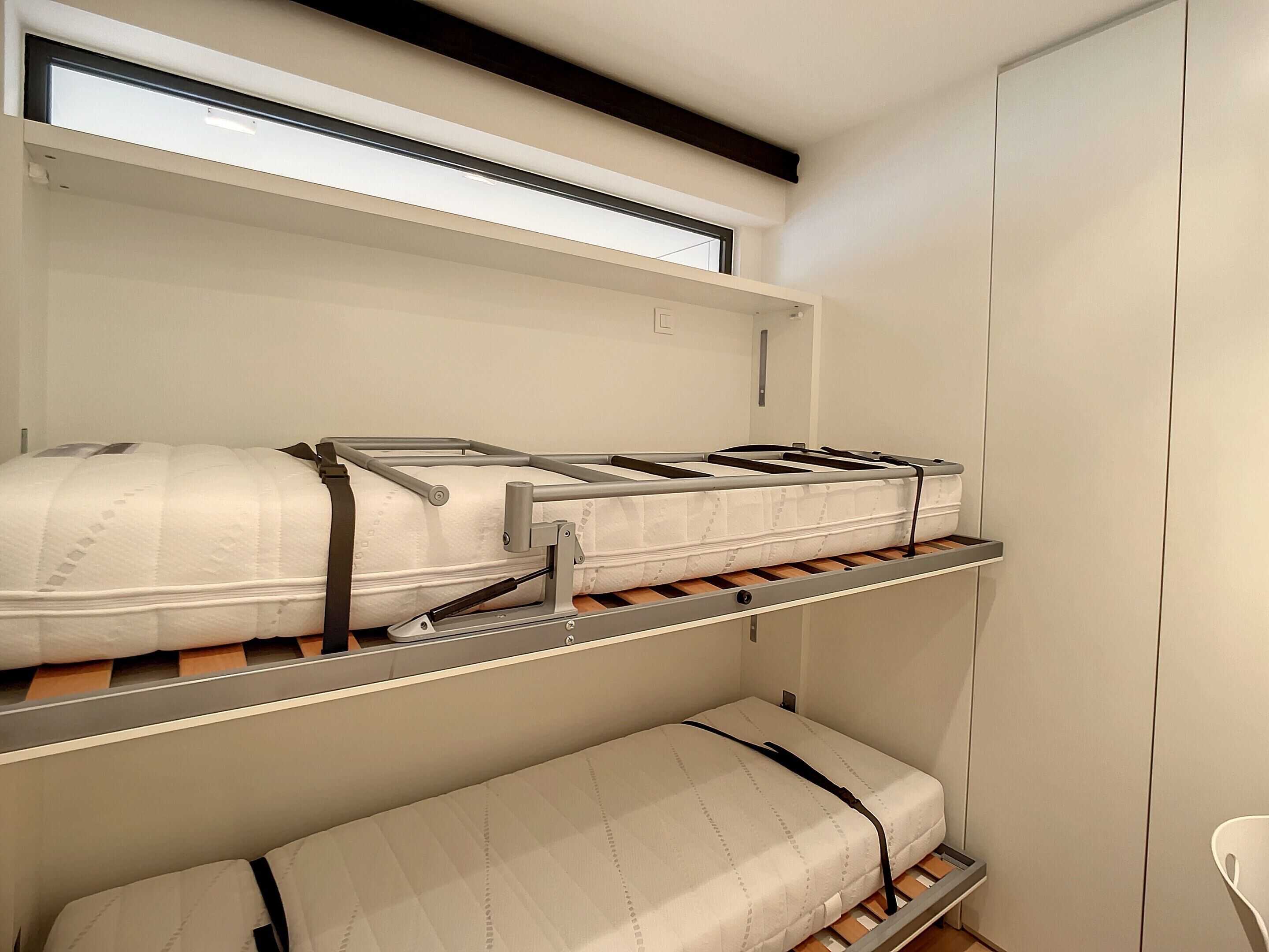 A bunk bed with a mattress on the top bunk and a single bed on the bottom.