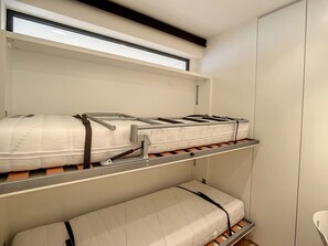 A bunk bed with a mattress on the top bunk and a single bed on the bottom.