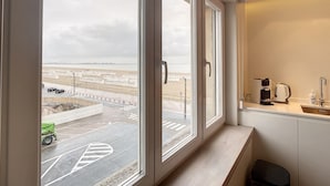 Ein Hotelzimmer mit großen Fenstern, einer Küchenzeile und Blick auf die Stadtlandschaft.